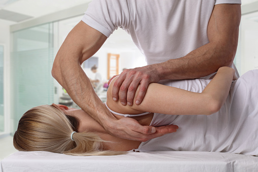 Woman having chiropractic back adjustment. Osteopathy, Alternative medicine, pain relief concept. Physiotherapy, sport injury rehabilitation